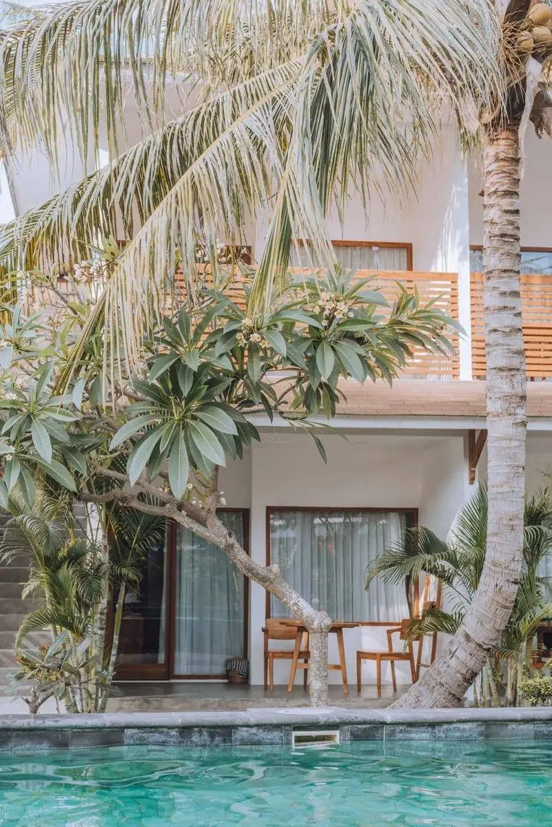 Palm trees and a turquoise pool beside white bungalows on Gili Air