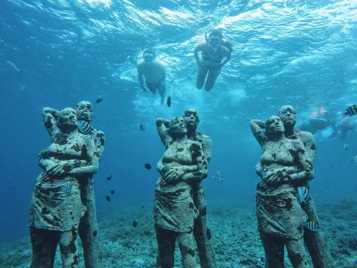 Snorkellers above underwater statues