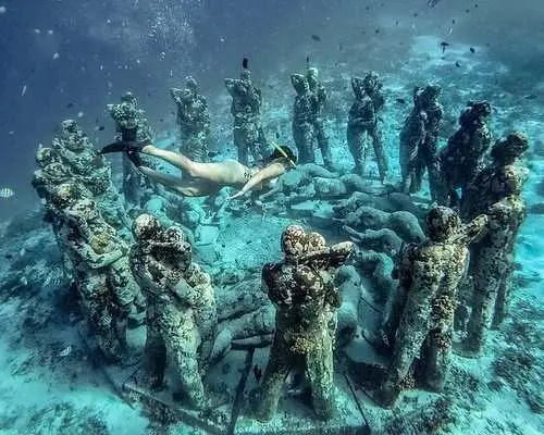 Underwater statues on the seabed with a snorkeller