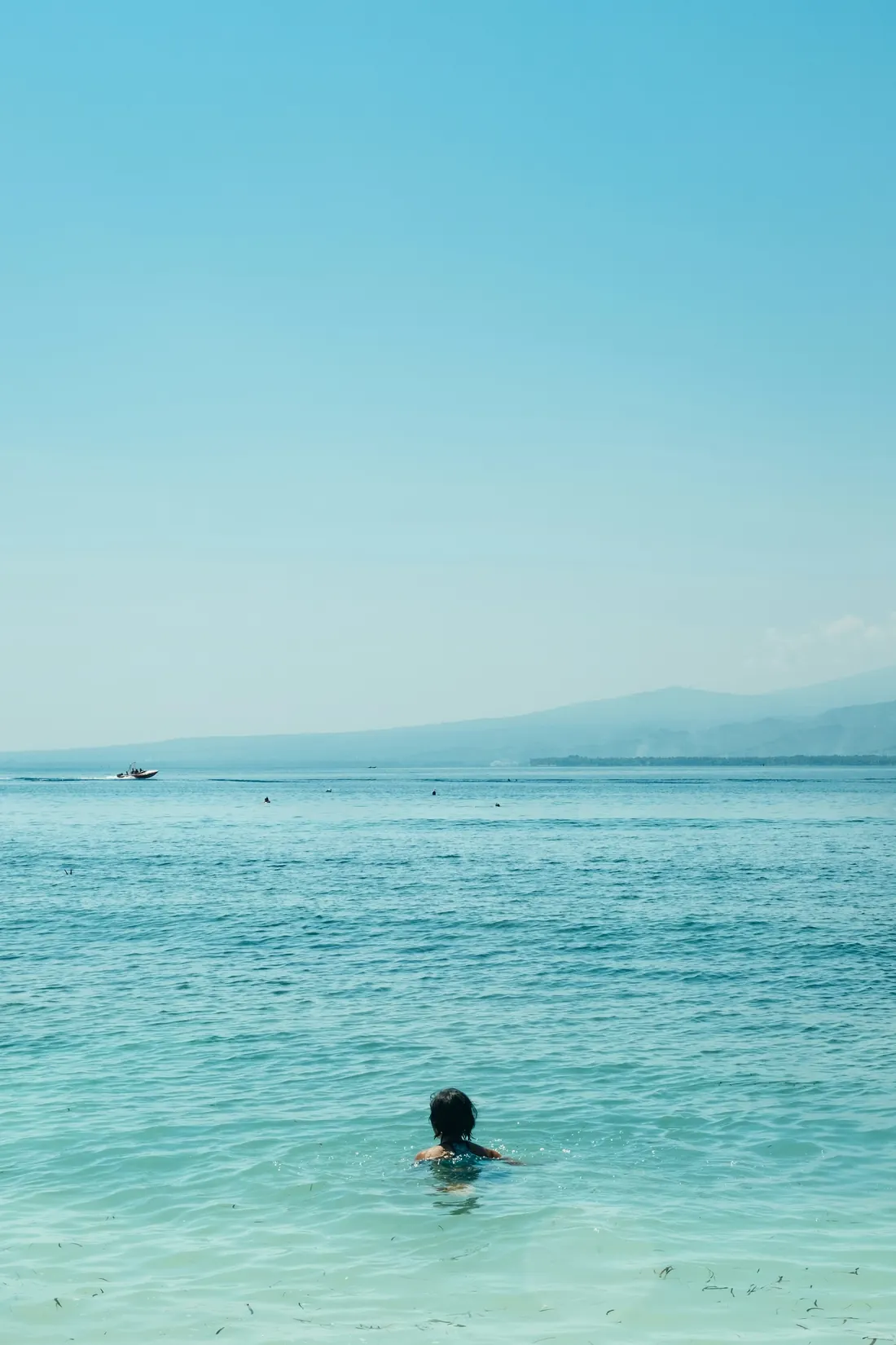 A person swimming alone in the turquoise sea off Gili Air