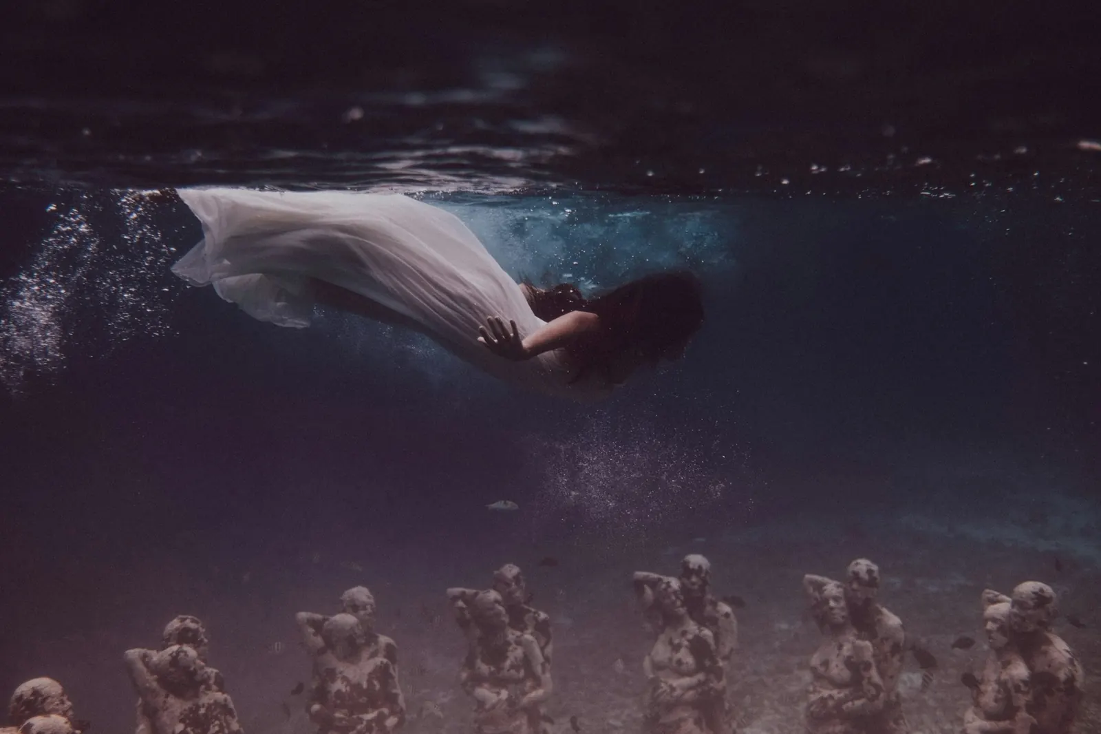 A woman floating underwater near the statues off Gili Meno, on this trip’s shared snorkel route