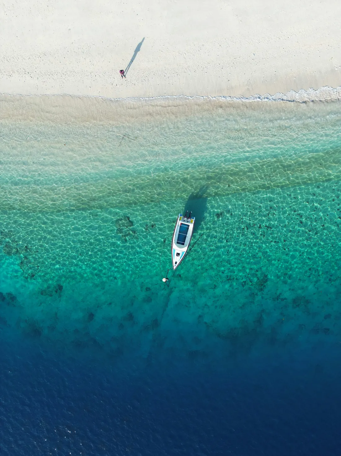 A boat over the clear shallows at Turtle Point, Gili Trawangan, from above