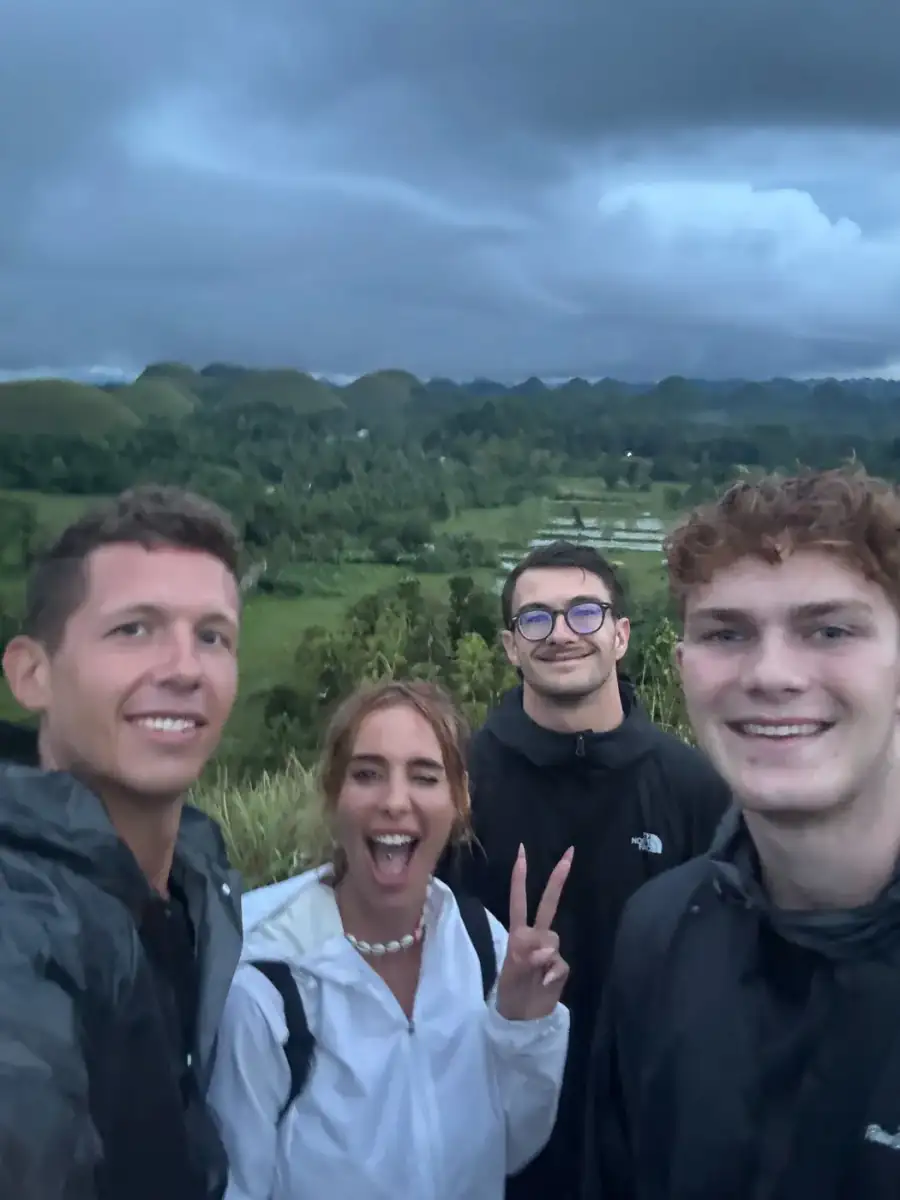 Four guests smiling on a hilltop day out