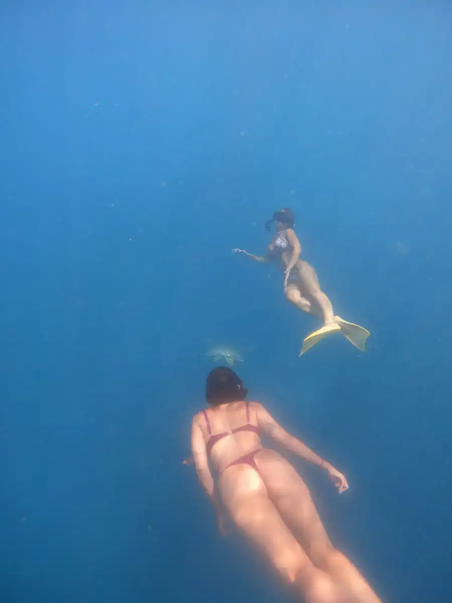 Two freedivers swimming in clear blue water