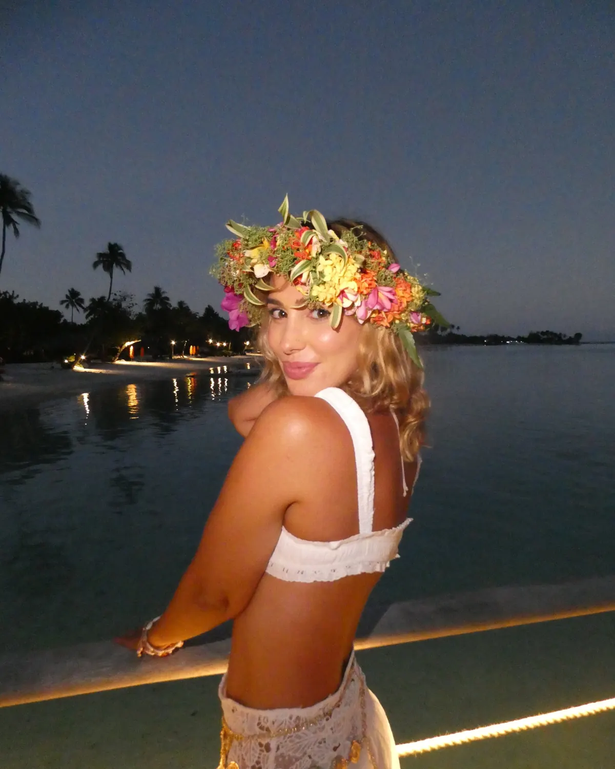 Rocío in a fresh Tahitian flower crown by the lagoon at dusk